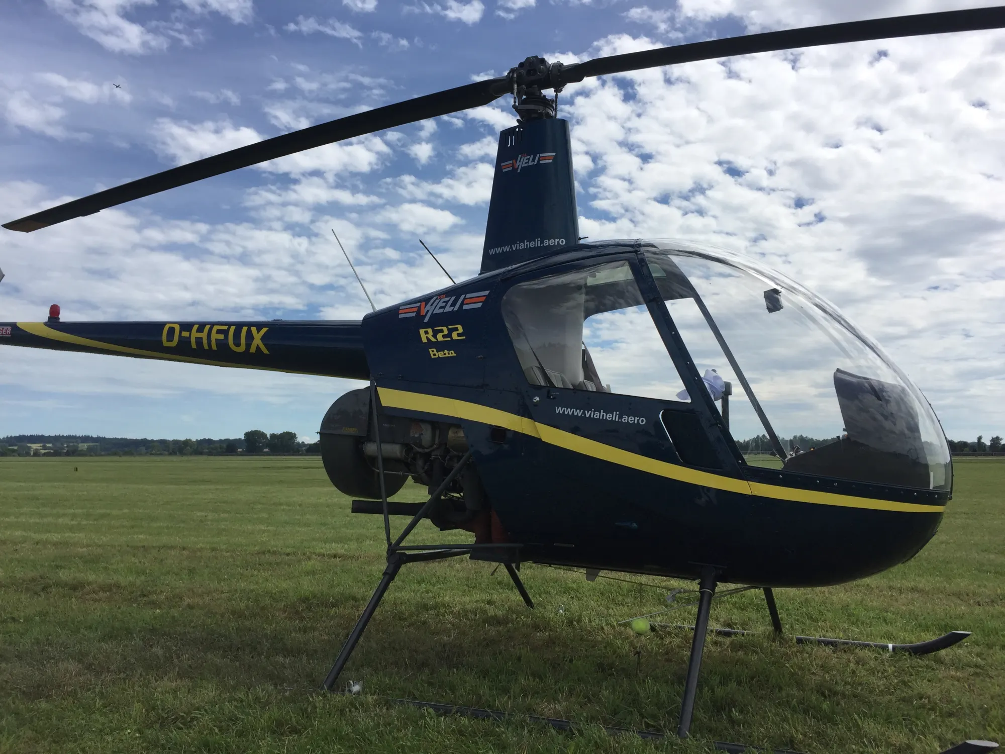 Dunkelblauer Robinson-Hubschrauber auf einer Graspiste