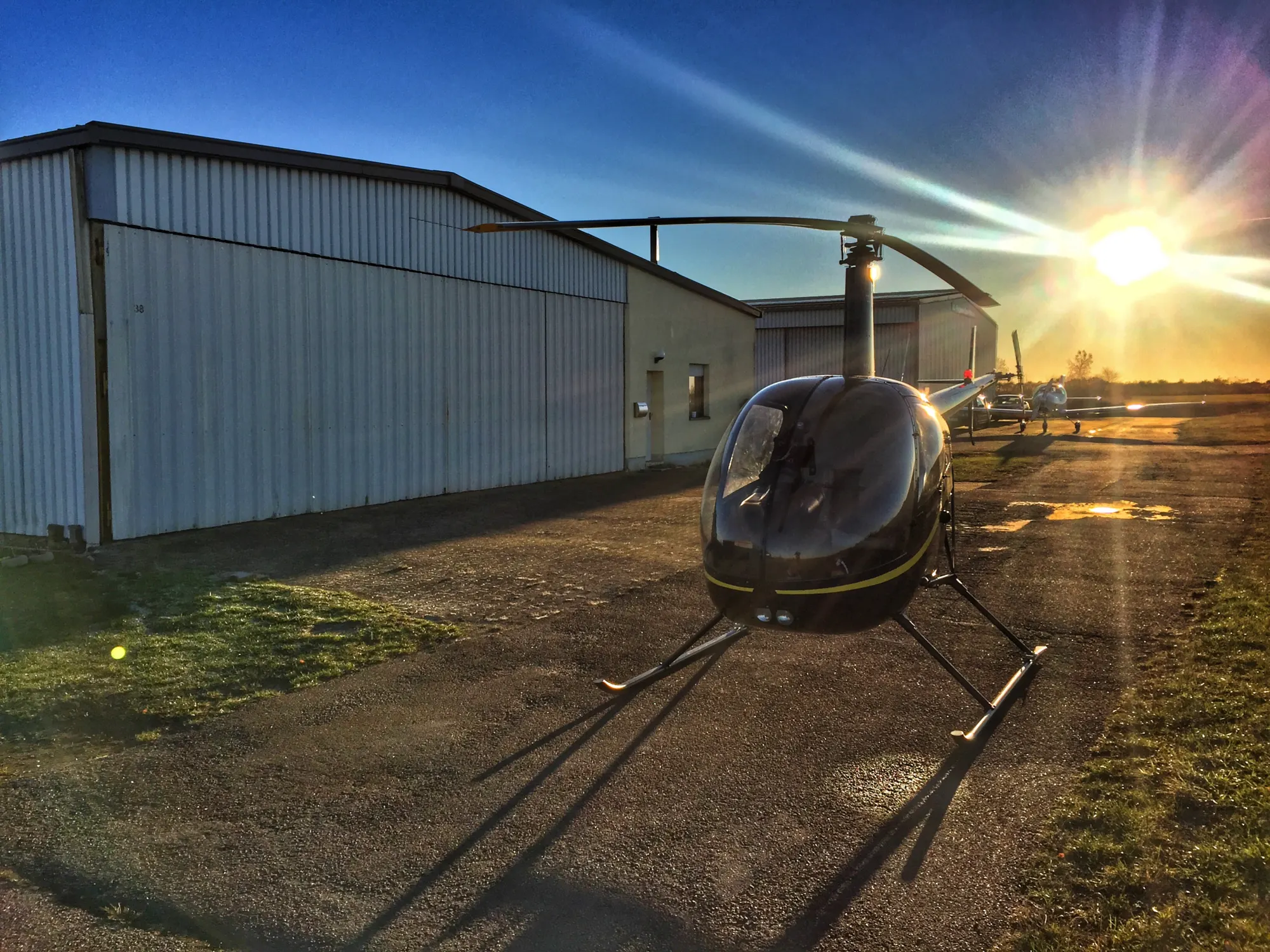 Robinson R22 vor einer Halle im Gegenlicht