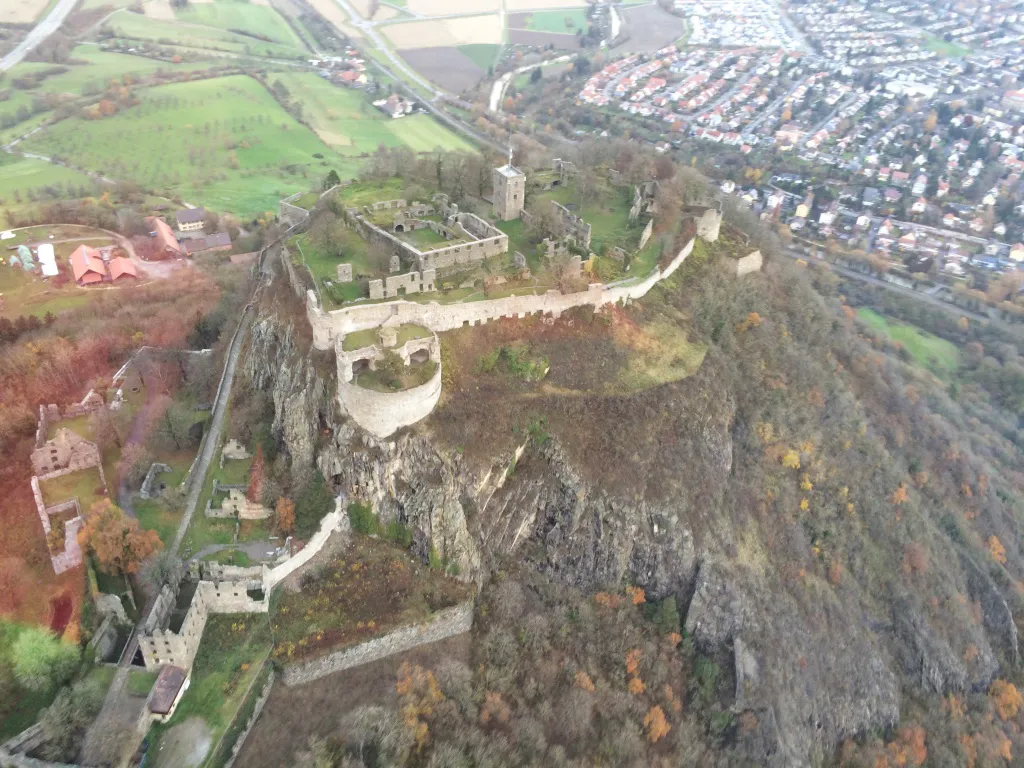 Luftbild einer Burgruine auf einem bewaldeten Felsen
